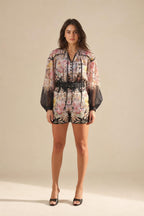 Front view of model wearing floral print long sleeve romper with black belt
