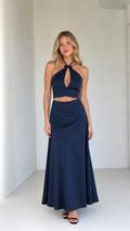 Front view of model wearing navy satin halter crop top and maxi skirt set