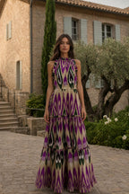 Front view of model wearing purple multi ikat print maxi dress in a courtyard