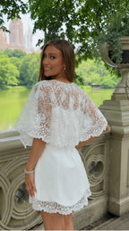 Back three-quarter view of white lace cape sleeve mini dress with scalloped hem