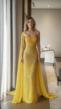 Front view of yellow one-shoulder beaded evening gown with cape