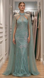 Front view of model wearing sage green embellished evening gown with cape