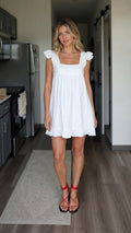 Front view of woman wearing white square neck babydoll mini dress