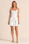 Front view of white embellished square neck mini dress with bow straps