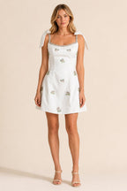 Front view of white embellished square neck mini dress with bow straps