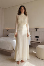 Front view of woman wearing cream pleated high-neck long-sleeve maxi dress