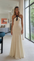 Front view of Ivory halter neck maxi dress with black bow