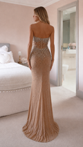 Back view of woman wearing champagne strapless embellished mermaid gown