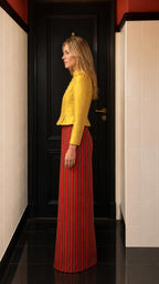 Side profile view of yellow jacket and striped maxi skirt set