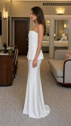 Side profile of woman in white strapless dress showing peplum detail