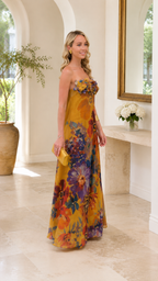 Angled view of mustard floral strapless maxi dress with flowing skirt