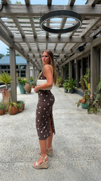 Side view of chocolate brown polka dot fitted midi dress with back slit