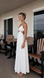 Side profile view of woman in white maxi dress on balcony