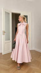 Angled front view of blush pink sleeveless tie neck midi dress with flared skirt