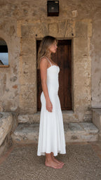 Side profile view of woman in white midi dress