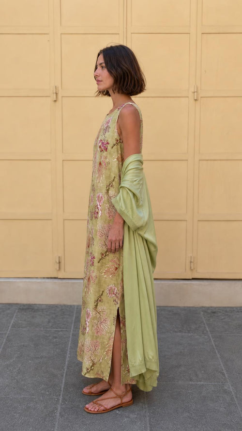 Side profile of model in olive floral maxi dress showing side slit