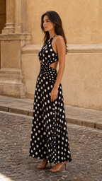 Side view of black polka dot halter maxi dress with side cutout and flowing skirt