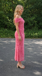 Model wearing pink off-the-shoulder ruched floral midi dress, side view