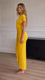 Side profile view of model in yellow maxi dress showcasing the drape
