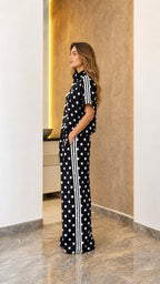 Model wearing black polka dot track set, side view