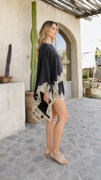 Model wearing black lace trim poncho and shorts set, side view