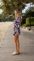 Burgundy floral wrap romper shown from the side with long sleeves and short length