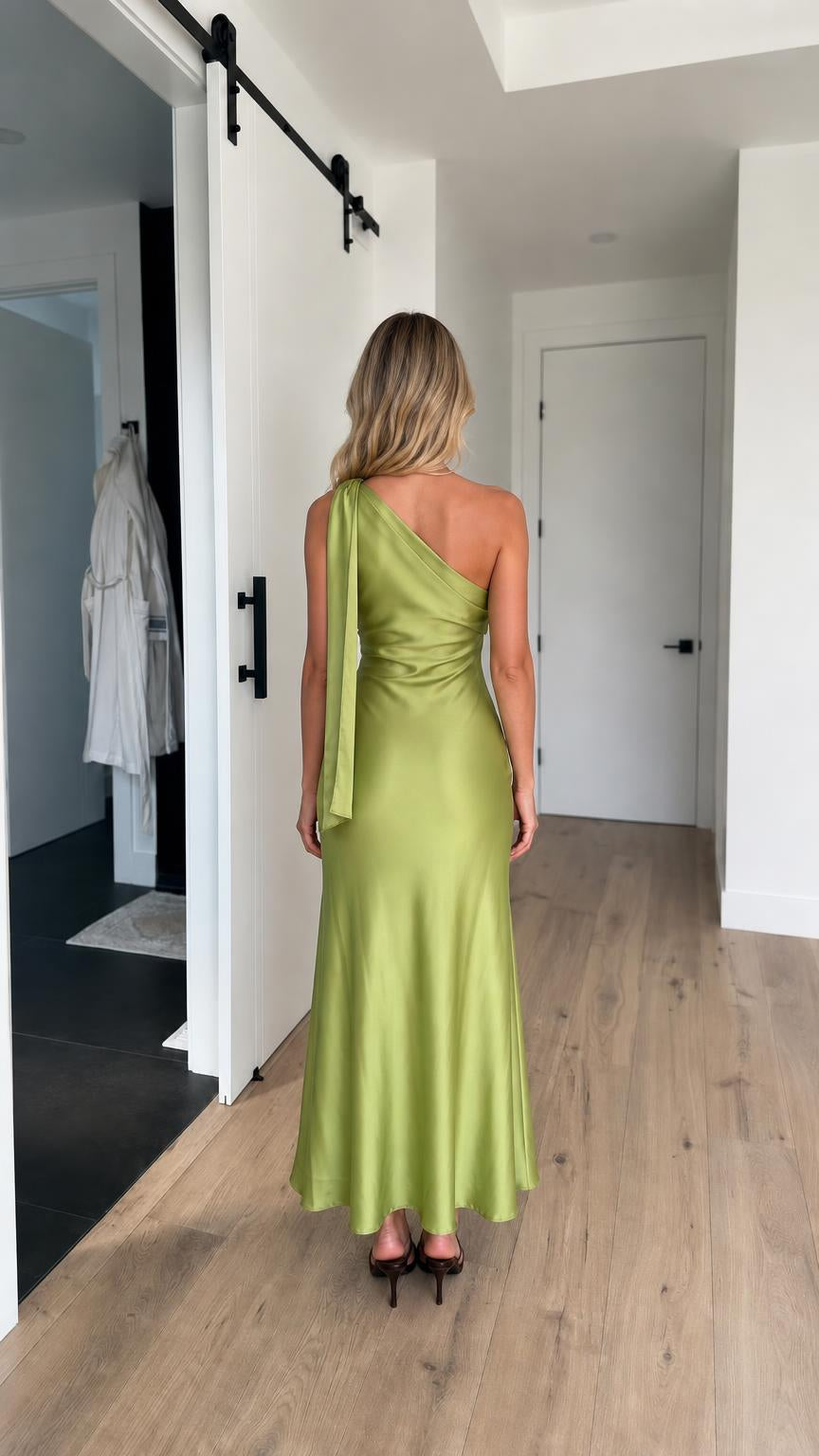Back view of model showing shoulder drape detail on green dress