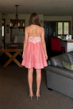 Back view of model wearing pink strapless mini dress with floral back detail