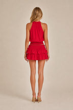 Back view of model in red halter top and tiered mini skirt