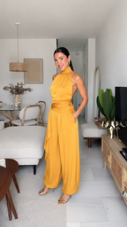 Angled front view of mustard halter jumpsuit with wide legs and side pockets