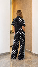 Model wearing black polka dot track set, back view