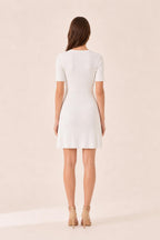 Back view of woman in white ribbed knit mini dress