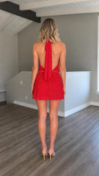Back view of model in red halter mini dress showing open back