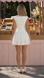 Model wearing white sleeveless drop-waist mini dress from back view