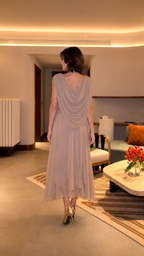 Back view of taupe draped midi dress showing flowing overlay and layered hem