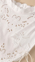Close-up detail of white eyelet embroidery and scalloped hem