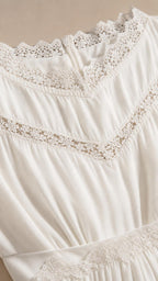 Close-up view of intricate crochet lace trim and fabric texture on white dress