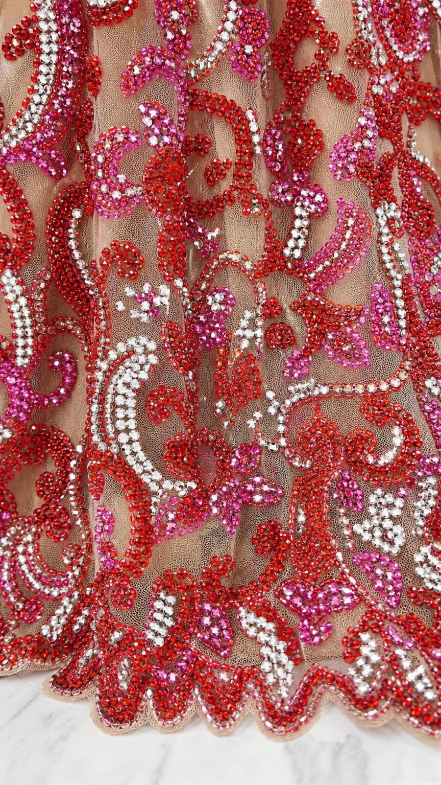Close up of intricate red and pink beadwork on mesh
