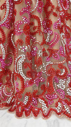 Close up of intricate red and pink beadwork on mesh