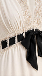 Close-up detail of lace neckline and black bow waist accent on ivory dress