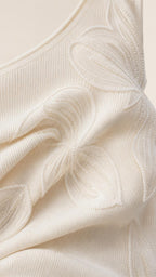 Close-up of textured fabric and floral appliques on white dress
