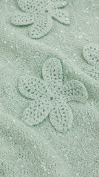 Close-up detail of mint green crochet floral applique and shimmer fabric