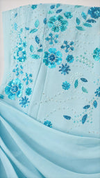 Close-up of floral sequin and bead embroidery on light blue fabric