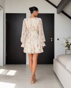 Back view of ivory floral long sleeve mini dress with gathered waist