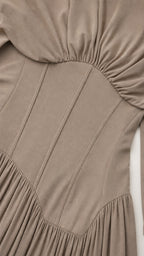 Close-up detail of structured corset waist and pleated fabric on taupe dress