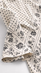 Close up fabric detail of cream dress with dot and floral pattern