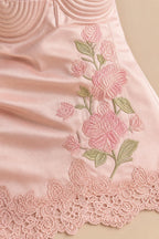 Close-up detail of floral embroidery and lace hem on satin dress
