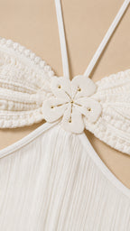Close-up detail of white bodice with floral appliqué and halter straps