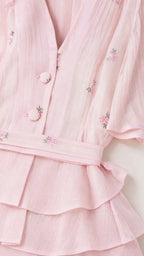 Close-up detail of V-neck, buttons, embroidery, and peplum tiers