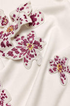 Close-up of 3D embroidered floral appliques on smooth white fabric